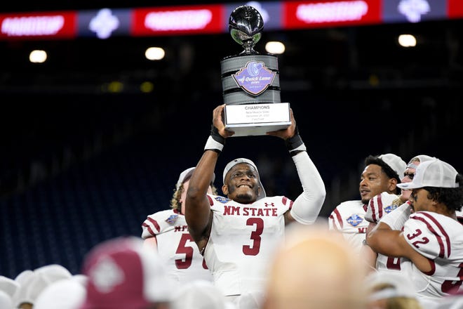 Dec 26, 2022; Detroit, Michigan, USA; New Mexico State University linebacker Chris Ojoh (3) hoists the Quick Lane Bowl trophy over his head as he and his teammates celebrate their win over Bowling Green State University in the 2022 Quick Lane Bowl at Ford Field.
