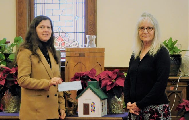 Lillian Haddad, left, of St. Mary's Food Pantry, and Cindy Taylor, right, of Cadmus Presbyterian Church's Mission committee, are pictured during the Dec. 18 church service when Cadmus Presbyterian presented more than $400 to the Adrian food pantry as part of this year's House of Change fundraiser.