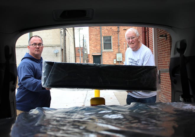 Jonathan Chessman (left) and John Chessman load a new mattress into John's SUV. Father and son are volunteers for the Now I Lay Me Down bed ministry, a program started by the First Presbyterian Church.