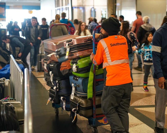 A Southwest worker pushes a cart full of bags to a storage area at Denver International Airport on Tuesday, Dec. 27, 2022.