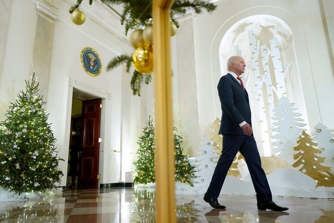 President Joe Biden is reflected in a mirror as he walks to the East Room of the White House to speak ahead of the holidays, Thursday, Dec. 22, 2022, in Washington.