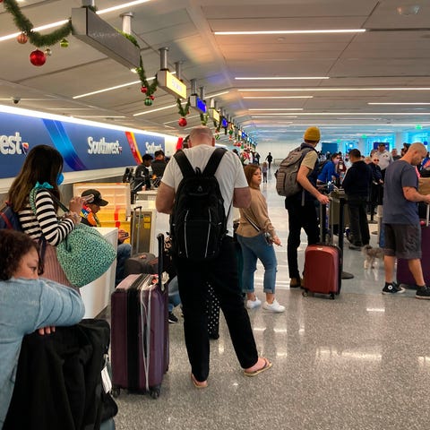 Travelers wait at a Southwest Airlines baggage cou