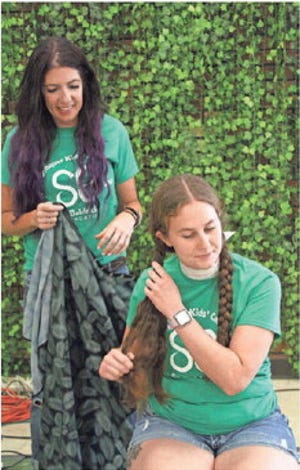 Last June, hairstylist Michelle Villemonte, left, prepares to cut about 12 inches of Taylor Sattler’s hair to be donated to Children With Hair Loss in South Rockwood.