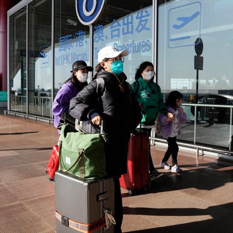 FILE - Passengers wearing masks walk through the C