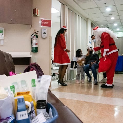 Hospital staff dressed up as Santa Claus greet a c