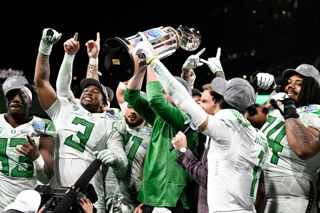 Oregon coach Dan Lanning lifts the trophy as players celebrate after Oregon defeated North Carolina 28-27 in the Holiday Bowl NCAA college football game Wednesday, Dec. 28, 2022, in San Diego.