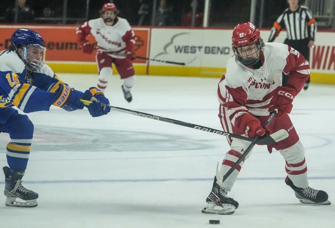 Wisconsin forward Cruz Lucius (right) fights for possession of the puck with Lake Superior State forward Jared Westcott during the Kwik Trip Face-Off Tournament on Dec. 28, 2022, at Fiserv Forum in Milwaukee.