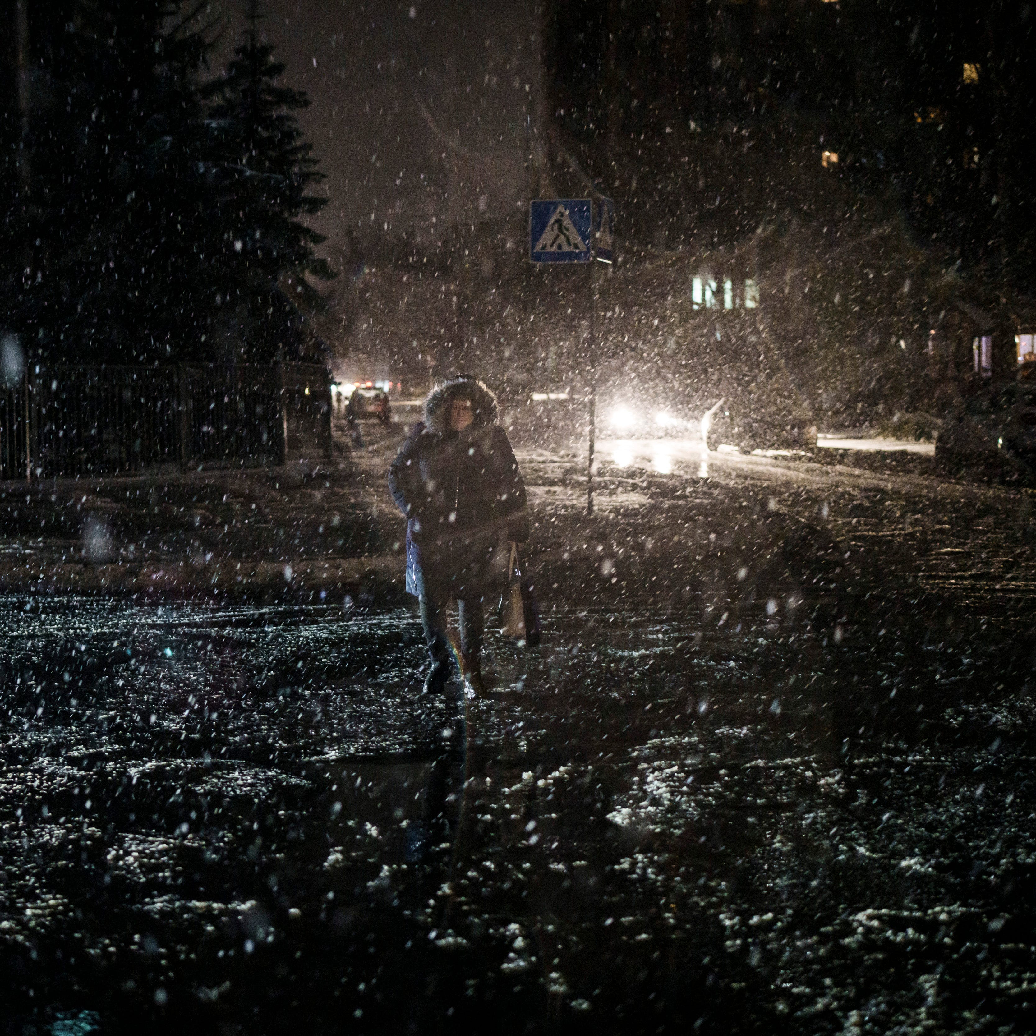 FILE - A woman crosses the street during snowfall, as power outages continue in Kyiv, Ukraine, Friday, Dec. 16, 2022. Russia's repeated attacks on Ukraine's energy infrastructure have left millions of civilians in the cold and the dark as temperatures plummet. (AP Photo/Felipe Dana, File) ORG XMIT: NY551
