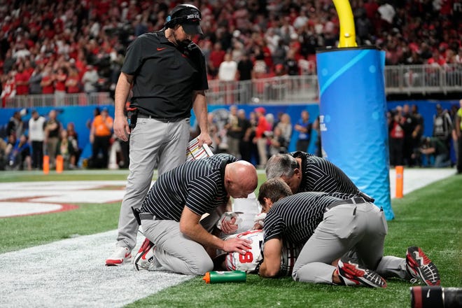 Ohio State coach Ryan Day checks on wide receiver Marvin Harrison Jr. as he is tended to by medical staff.