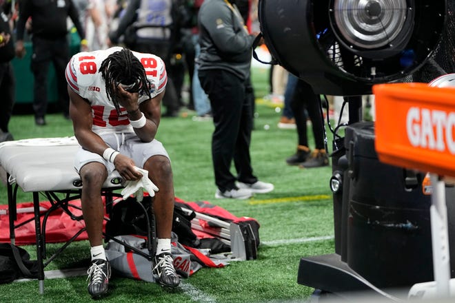 Ohio State receiver Marvin Harrison Jr., who was knocked out of the game in the third quarter, holds his head on the bench after Saturday's loss to Georgia.