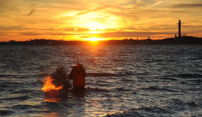 Jay Critchley, Director of the International Re-Rooters Society, drags a burning Christmas tree underwater as the finale of the 35th Annual Re-Rooters Day Ceremony held in 2018.