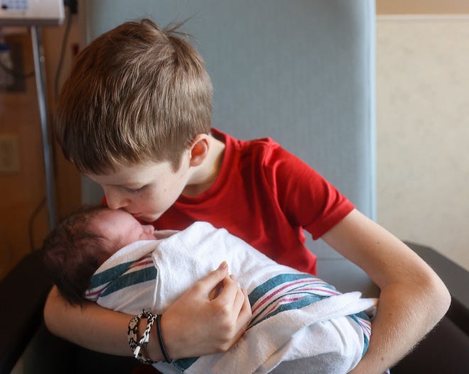 Big brother Daniel kisses his baby sister Natalie on the forehead.