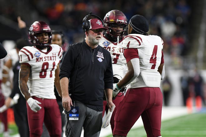 New Mexico State University head coach Jerry Kill, center, talks to players on the sidelines during the 2022 Quick Lane Bowl.
