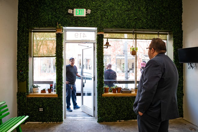 Art gallery and bar co-owner Carlos I. Villarreal stands in the doorway of Produce Bar Co. and speaks with co-owner John D. Garcia, on Jan. 3, 2023, in Corpus Christi, Texas. The Peoples Street venue is set to open Friday, Jan. 6, during the ArtWalk. Beer and wine will be available and it will feature fine art photography by Villarreal.