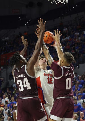 Jan 4, 2023; Gainesville, Florida, USA; Texas A&M Aggies forward Julius Marble (34) and guard Dexter Dennis (0) defend Florida Gators forward Colin Castleton (12)  during the second half at Exactech Arena at the Stephen C. O'Connell Center. Mandatory Credit: Kim Klement-USA TODAY Sports