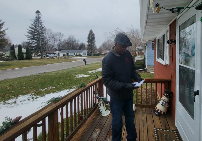 All Nations Pastor Vincent Mathews, holding a handful of pamphlets, awaits an answer at the door of a home nearby the church on Thursday, Dec. 29, 2022, while canvassing the neighborhood about the church serving as a temporary men's homeless shelter.