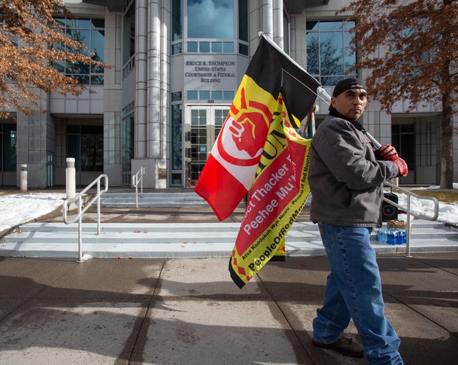 A protester holds a flag for the American Indian Movement and the protection of Peehee Mu'huh, also known as Thacker Pass, outside the Bruce R. Thompson Courthouse in Reno on Jan. 5, 2023.