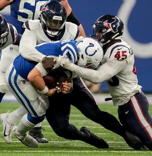 Houston Texans defenders including Houston Texans linebacker Ogbonnia Okoronkwo (45) work to bring down Indianapolis Colts quarterback Sam Ehlinger (4) on Sunday, Jan. 8, 2023, during a game against the Houston Texans at Lucas Oil Stadium in Indianapolis.