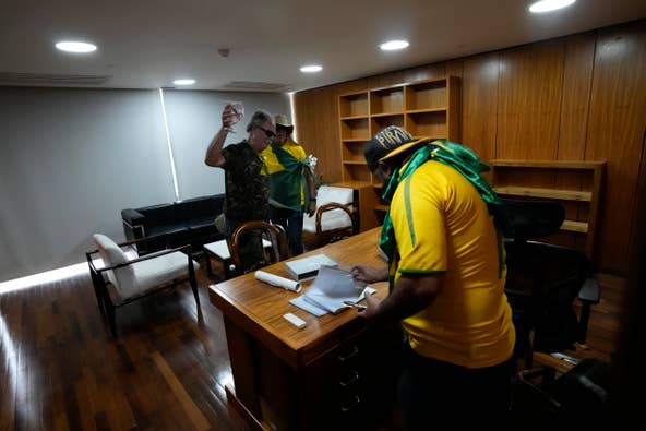 Protesters, supporters of Brazil's former President Jair Bolsonaro, rifle through papers on a desk after storming the Planalto Palace in Brasilia, Brazil, Sunday, Jan. 8, 2023. Planalto is the official workplace of the president of Brazil.