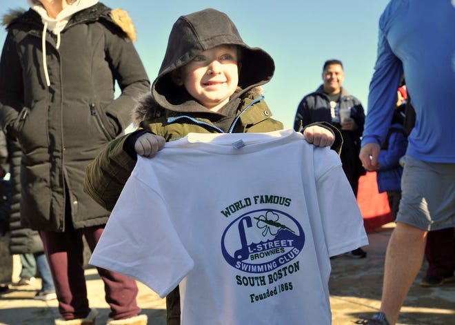 Quinn Waters, of Weymouth, also known as "The Mighty Quinn," holds a T-shirt presented to him by the L-Street Brownies Swimming Club of South Boston during the third annual North Quincy Polar Plunge at Wollaston Beach, Quincy, to benefit his cancer battle, Sunday, Jan. 8, 2023.
