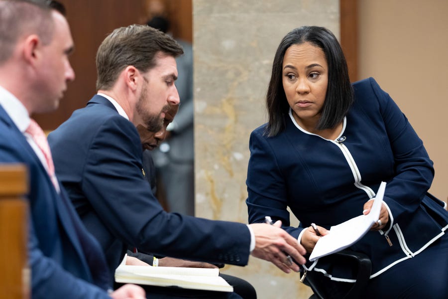 Fulton County District Attorney Fani Willis, right, talks with a member of her team during proceedings to seat a special purpose grand jury in Fulton County, Georgia, on May 2, to look into the actions of former President Donald Trump and his supporters who tried to overturn the results of the 2020 election. The hearing took place in Atlanta.