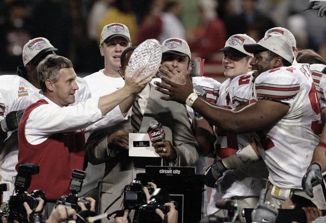 Ohio State University head football coach Jim Tressel hands the 2002 national championship trophy to defensive end Kenny Peterson. The Buckeyes won the National Football Championships at the Sun Devil Stadium in Tempe, Arizona, on Jan. 3, 2003.