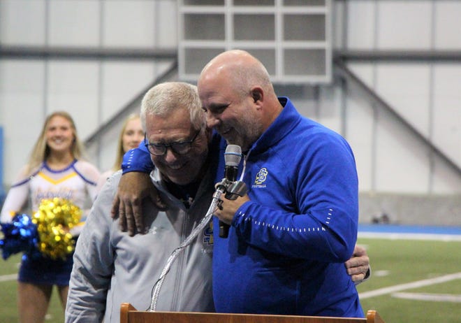 SDSU athletic director Justin Sell (right) hugs coach John Stiegelmeier at the national championship celebration Tuesday night at the SJAC.