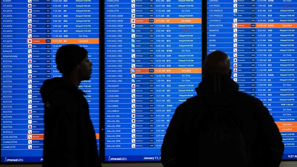 Travelers looks at a flight information display li