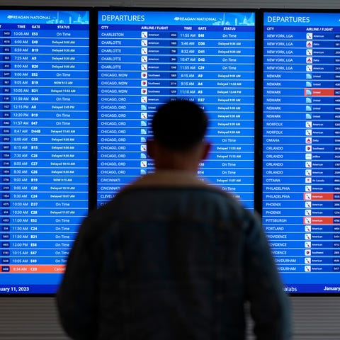 A traveler looks at a flight board with delays and