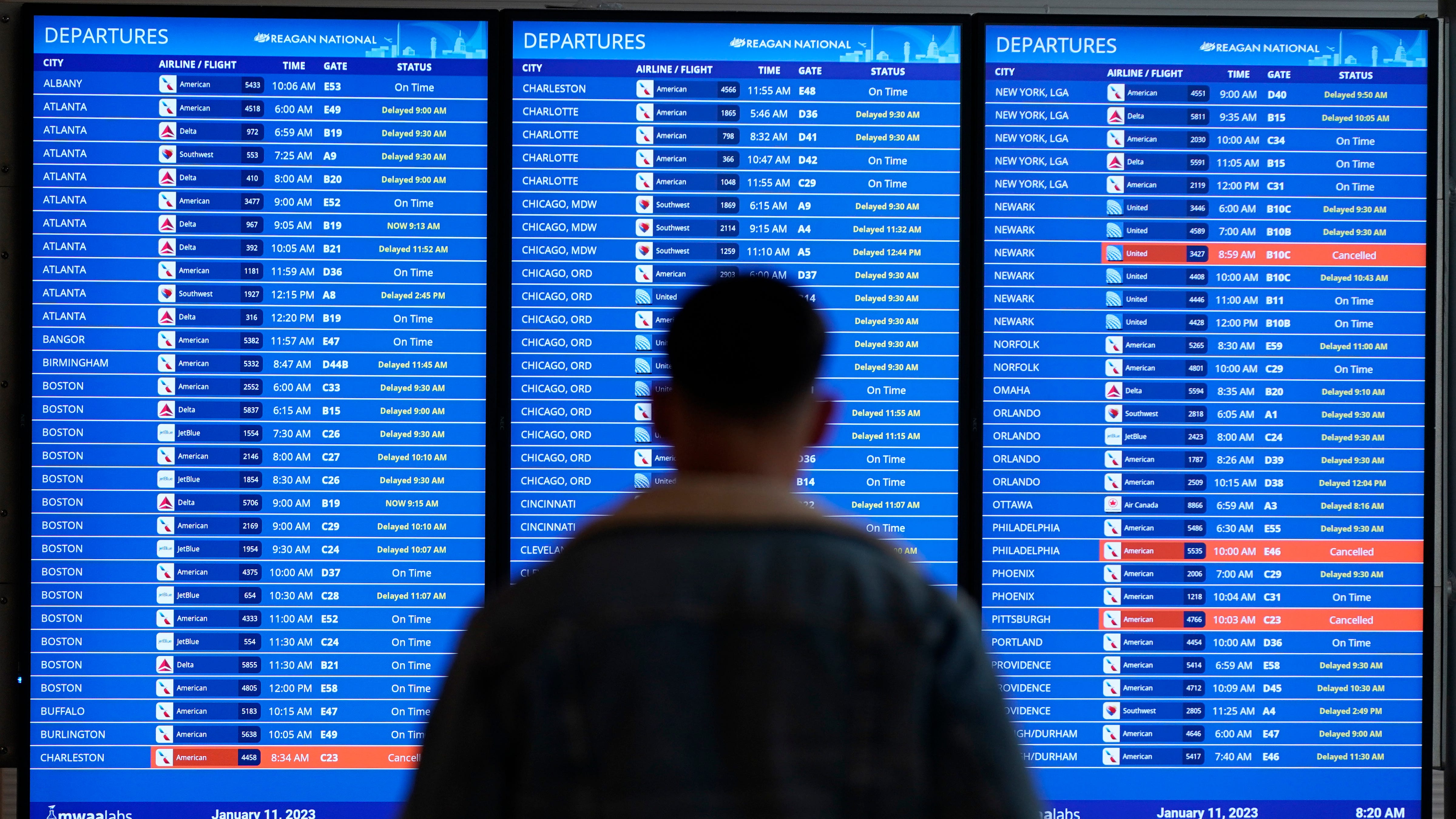 A traveler looks at a flight board with delays and cancellations at Ronald Reagan Washington National Airport in Arlington, Va., Wednesday, Jan. 11, 2023. Flights are being delayed at multiple locations across the United States after a computer outage at the Federal Aviation Administration.