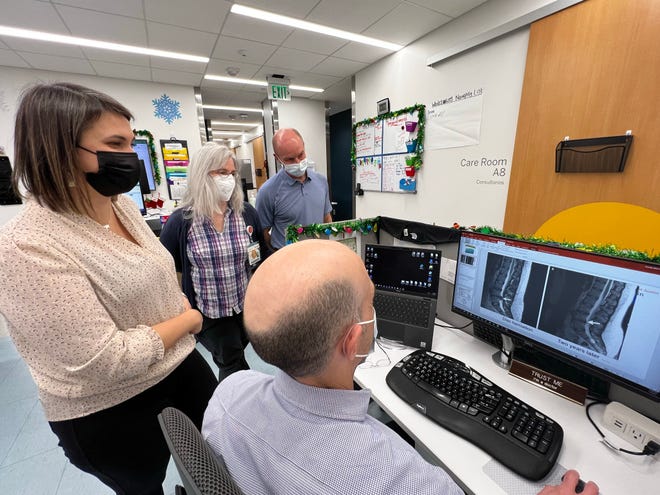 Dr. Mark Quaralt, front, social worker Mikaela Frisell, left, chiropractor Sylvia Dailey, center, and physical therapist Branden Dabell, right, discuss a patient at the Musculoskeletal Institute at UT Health Austin. A $1.2 million grant will put more social workers in UT Health clinics.