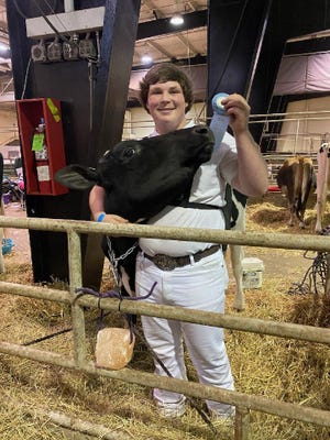 East Davidson High School student Preston Sechrest displays one of the ribbons he won showing dairy cattle at local and state competitions. He recently won a $1,000 grant from the National Future Farmers of America for his student project.