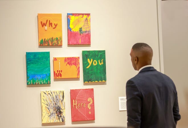 A visitor looks at a multi-panel piece in the “IDENTITY” exhibit at the National Veterans Memorial and Museum.