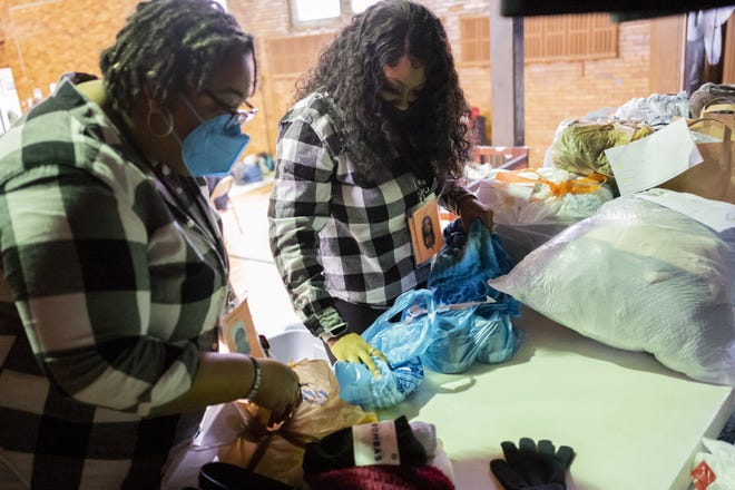 Angeleila Watkins, center, and Jess Smiley, left, both community health workers with the Columbus Coalition for the Homeless, sort clothes for distribution while at a warming station last year at Broad Street United Methodist Church.