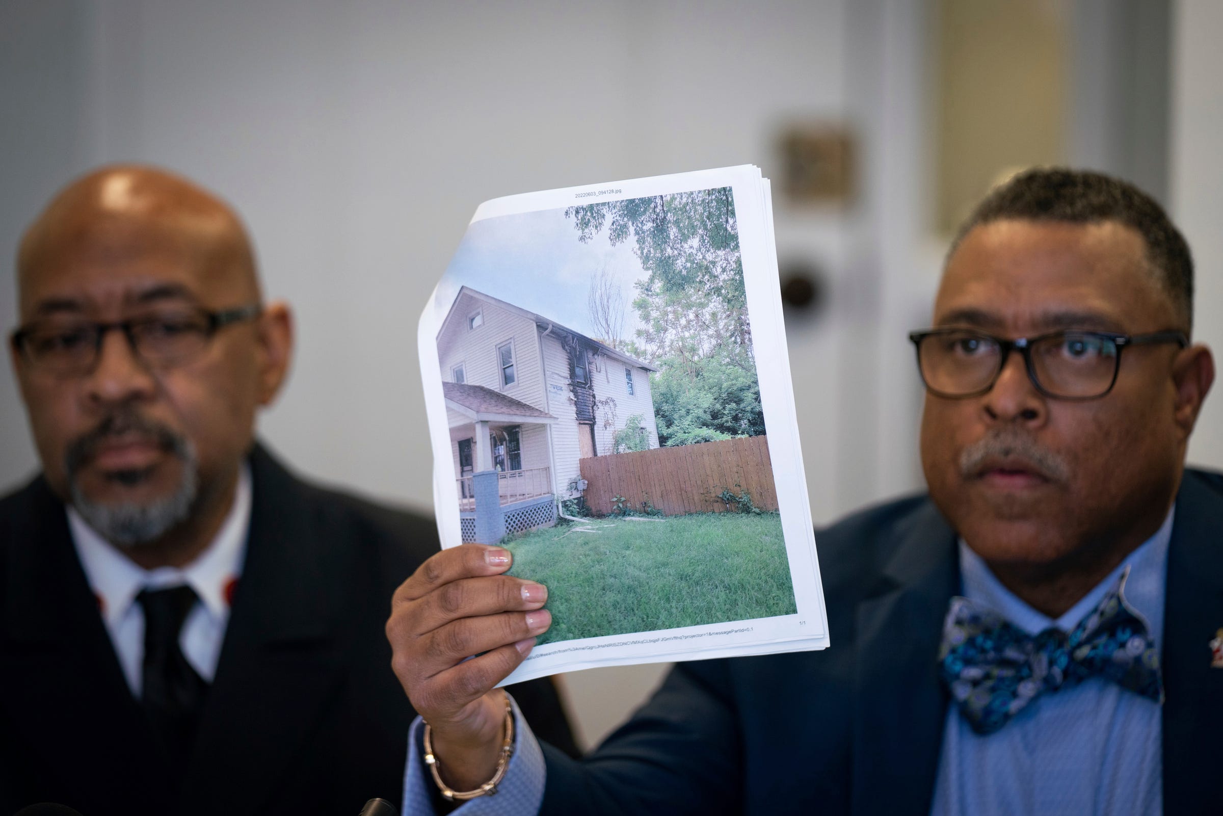Attorney Arnold Reed, right, shows a photograph of a Flint home that caught fire in May 2022, while flanked by Former Flint Fire Chief Raymond Barton during a press conference at the Arnold E. Reed & Associates, P.C. in Southfield on Monday, Jan. 9, 2023. Two brothers, Zyaire Mitchell, 12, and Lamar Mitchell, 9, died of smoke inhalation from the house fire.