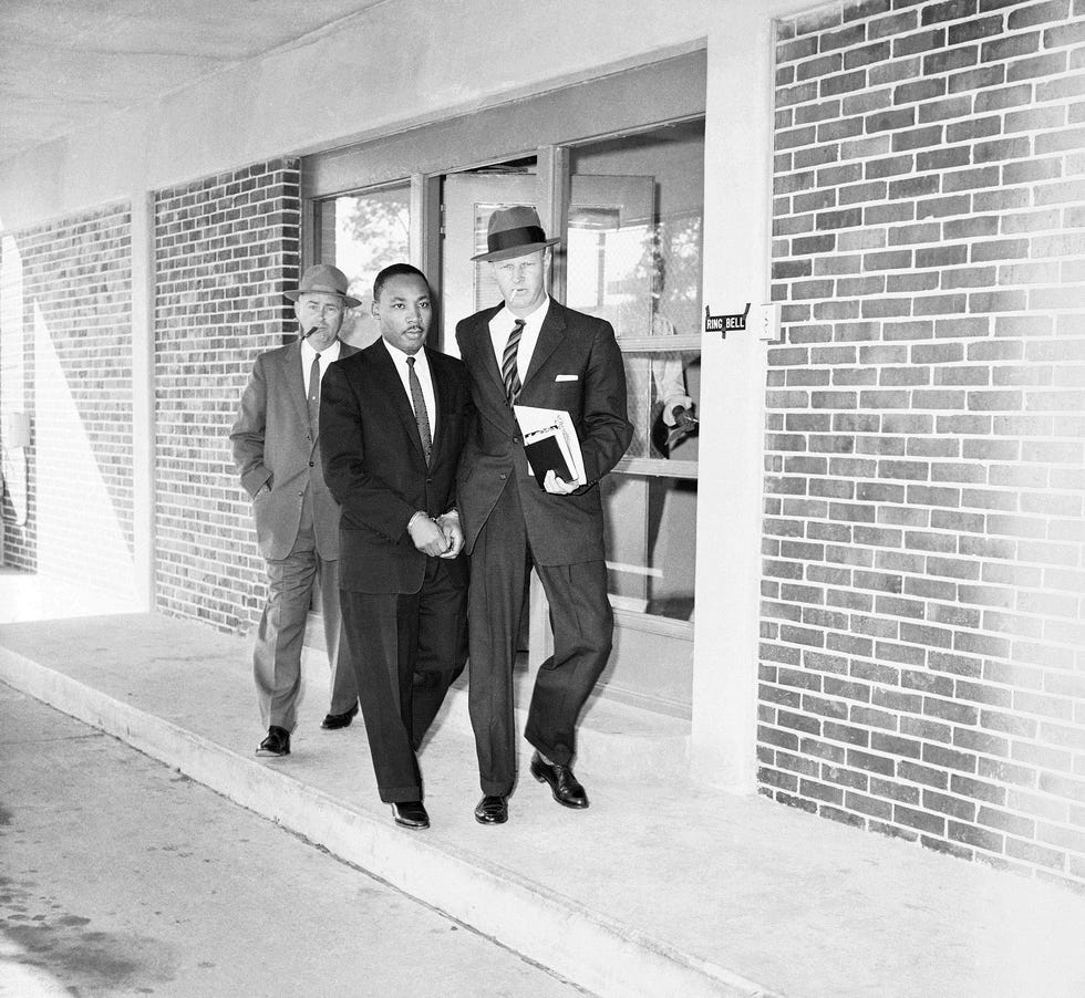Rev. Martin Luther King Jr. escorted from Fulton County, Ga., jail by two unidentified officers as he is taken to neighboring DeKalb County courthouse for a traffic hearing on Oct. 25, 1960.