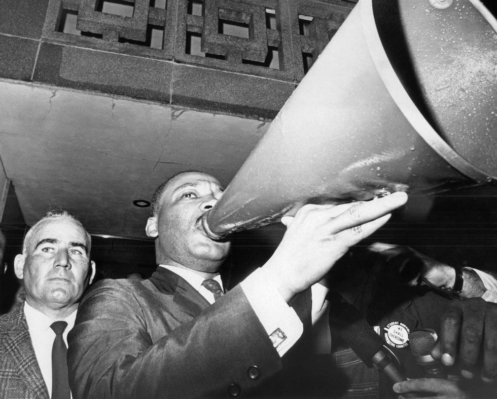 Dr. Martin Luther King Jr., uses a megaphone to address demonstrators assembled at the courthouse in Montgomery, Alabama, March 17, 1965 after a meeting with Sheriff Mac Butler left and other public officials. (AP Photo)