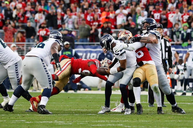 Seattle Seahawks quarterback Geno Smith fumbles while sacked by San Francisco 49ers defensive end Charles Omenihu during the second half of Saturday's wild card playoff game. The 49ers recovered the ball and Seattle could not keep it close for the rest of the game.