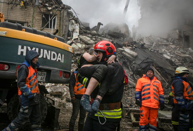 Emergency workers carry a wounded woman after a Russian rocket hit a multistory building in Dnipro, Ukraine.