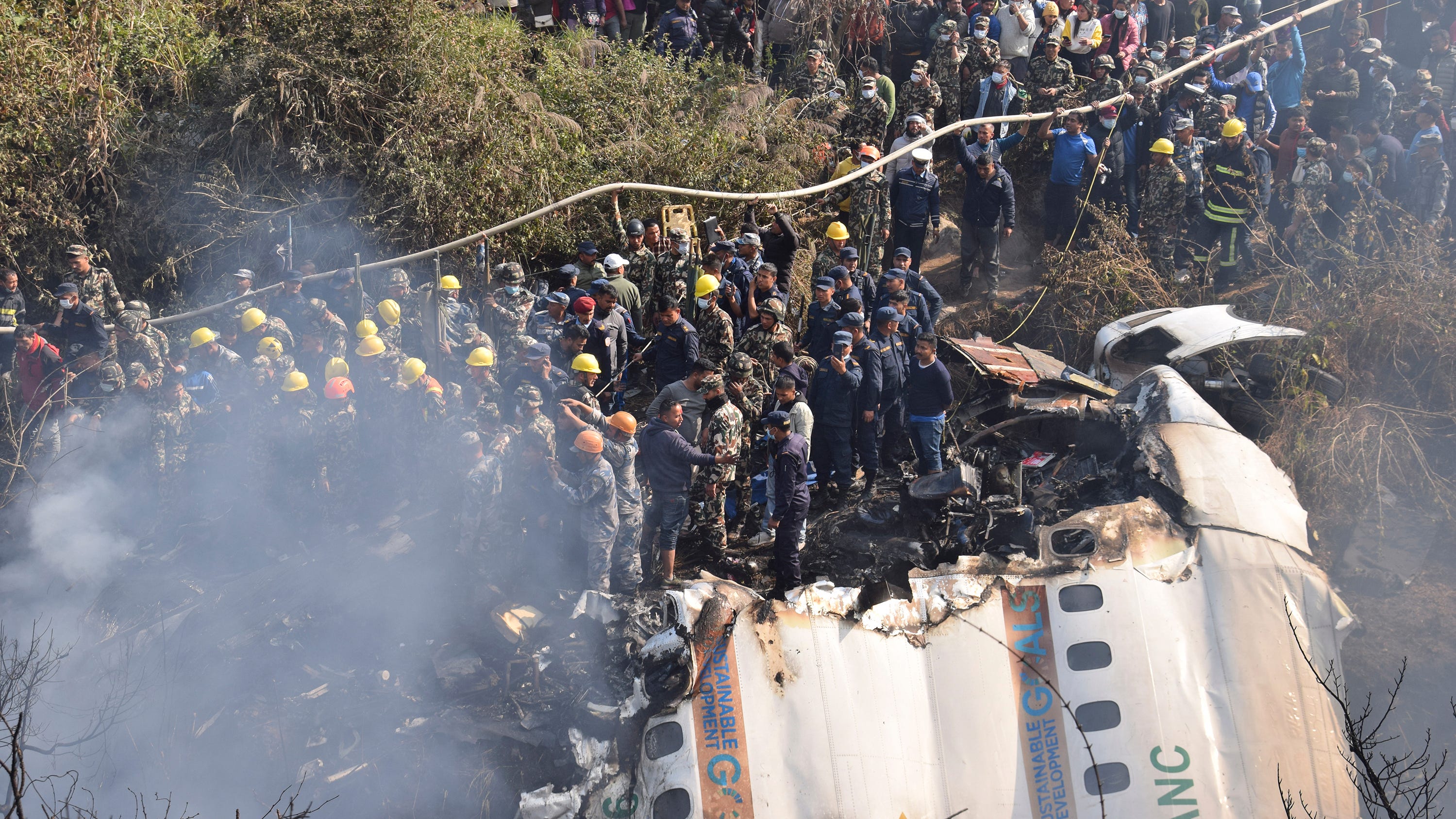 Nepalese rescue workers and civilians gather around the wreckage of a passenger plane that crashed in Pokhara, Nepal, Sunday, Jan. 15, 2023. 