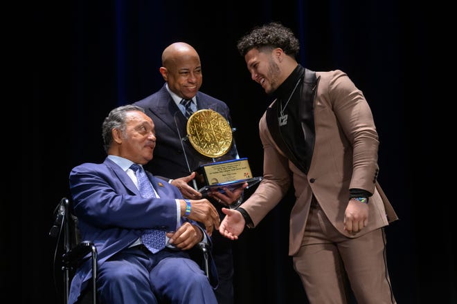The Rev. Jesse Jackson Sr., left, and Bishop Tavis Grant present the Collegiate Service Award to University of Michigan running back Blake Corum at the Let Freedom Ring Awards Celebration at the Fox Theatre in Detroit on Monday.