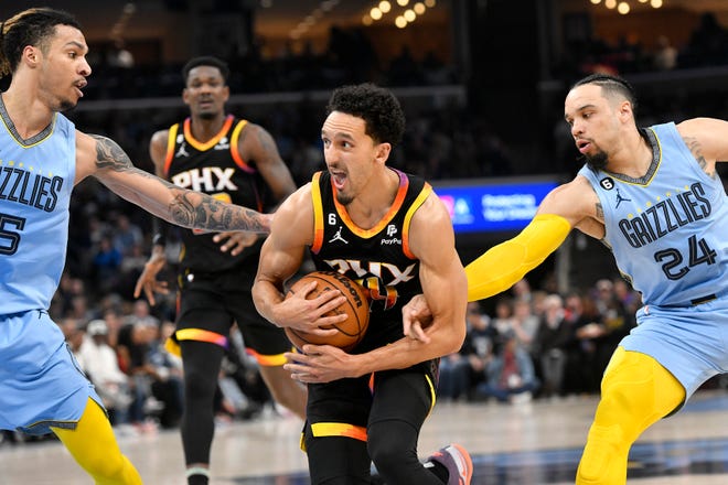 Phoenix Suns guard Landry Shamet, center, tackles the ball between Memphis Grizzlies forwards Brandon Clark, left, and Dillon Brooks (24) in the first half of an NBA basketball game Monday, Jan. 16, 2023, in Memphis, Figs.