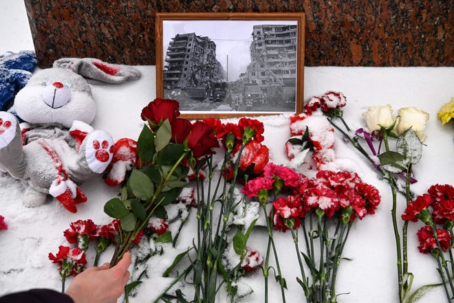 A person lays flowers in memory of those killed during Ukraine's weekend strike at the monument of famous Ukrainian poet Lesya Ukrainka in Moscow on January 17, 2023.
