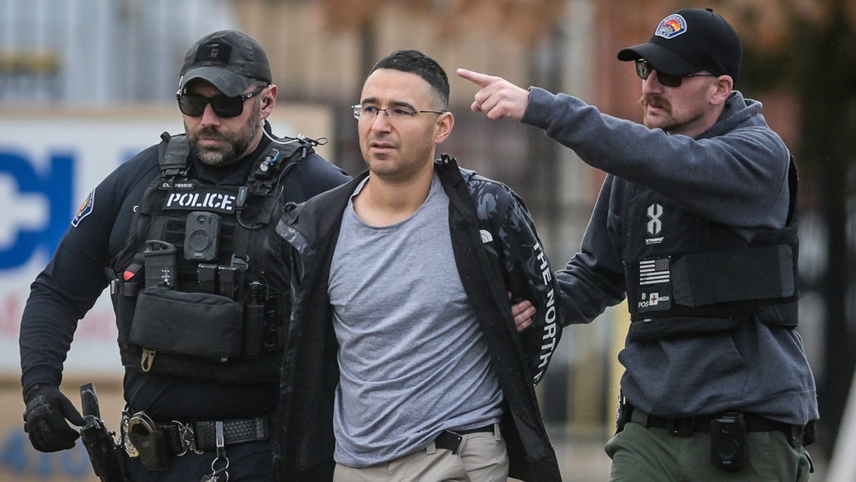 Solomon Pena, center, a Republican candidate for New Mexico House District 14, is taken into custody by Albuquerque Police officers, Monday, Jan. 16, 2023, in southwest Albuquerque, N.M. Pena was arrested in connection with a recent series of drive-by shootings targeting Democratic lawmakers in New Mexico.