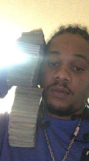 Convicted Alabama drug trafficker Rolando Williamson posing with stacks of cash in a photo used against him in federal court.