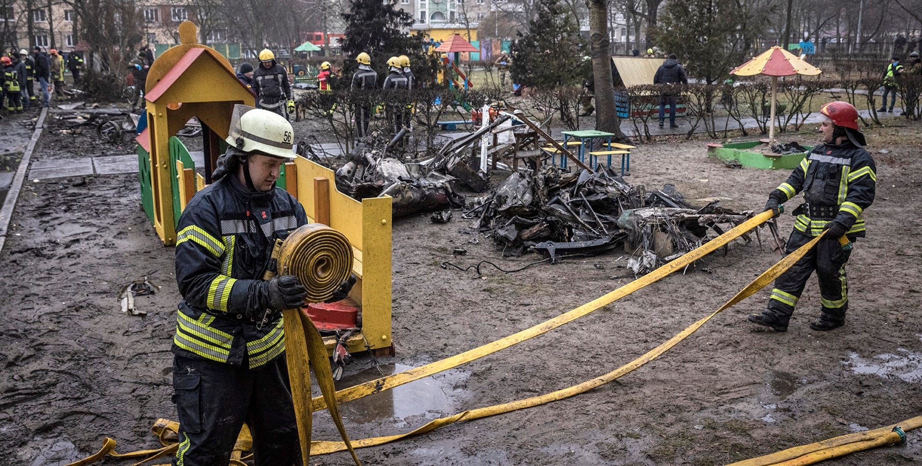 Firefighters work in the play area of a kindergarten facility strewn with debris from the crash.