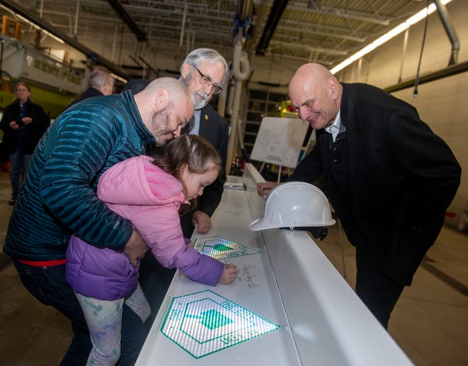 Eric Burt holds his daughter, Alexis Burt, 5 as she signs a beam on Wednesday that will be used to construct the. new Kent City Hall. Mayor Jerry Fiala and council member Roger Sidoti watch the signing.