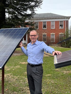 Craig Butler, executive director of the Muskingum Watershed Conservancy District, poses with solar panels similar to the ones that will be installed at area MWCD lakes in the near future.