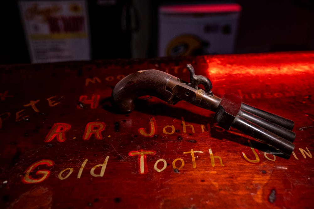 A triple-barreled pistol that was collected from a patron years ago rests on the bar above the names of lumberjacks who drank long ago at Stubb's Museum Bar in Ontonagon, located in Michigan's Upper Peninsula, on Wednesday, Oct. 19, 2022.