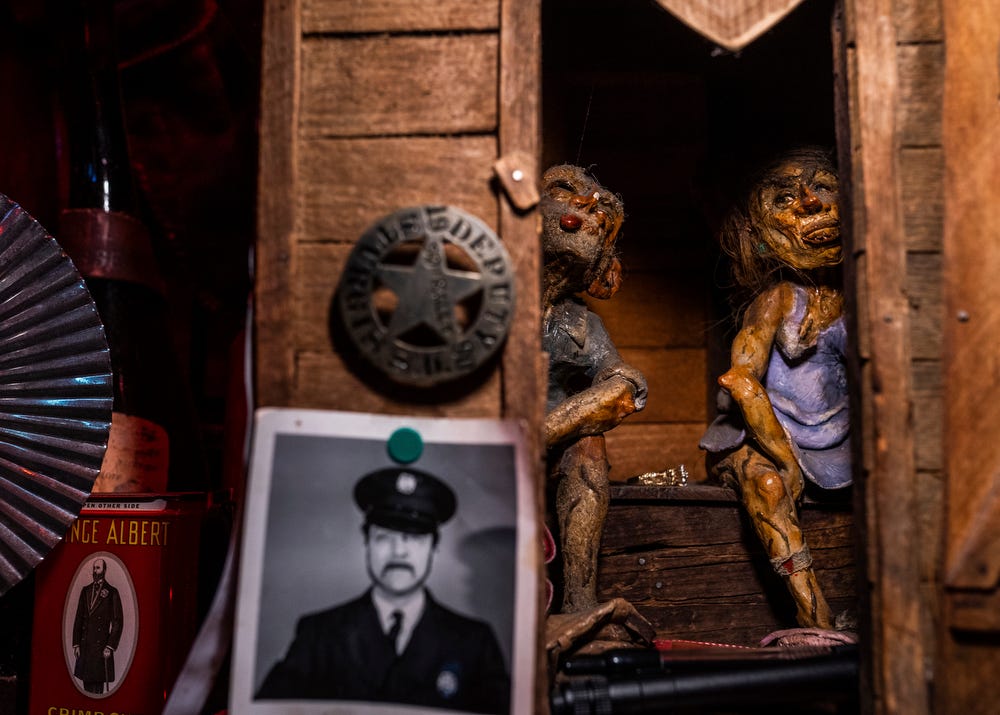 Hand-crafted characters crafted by a local man years ago from clay and human hair sit inside a miniature outhouse that's on display behind the bar at Stubb's Museum Bar in Ontonagon on Wednesday, Oct. 19, 2022.